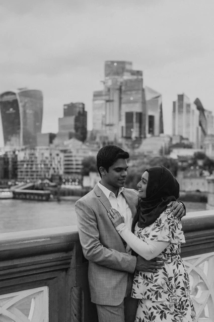 London engagement photoshoot: black-and-white close portrait with the skyline Black-and-white close portrait of a couple with the City skyline across the Thames behind them during their London engagement photoshoot.
