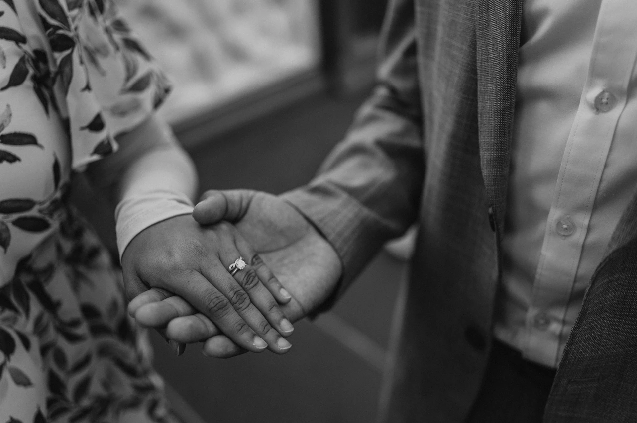 London engagement photoshoot: black-and-white detail of their engagement ring Black-and-white close-up of an engagement ring and the couple’s hands beside Tower Bridge’s railing during their London engagement photoshoot.