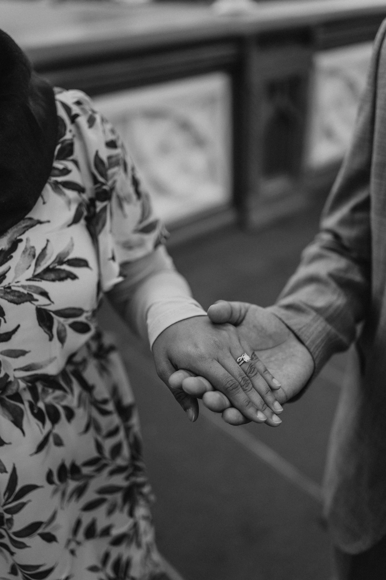 Black-and-white detail of a couple holding hands beside Tower Bridge’s railing during their London engagement photoshoot.