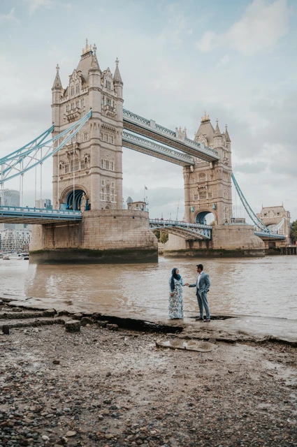 London engagement photoshoot: facing each other beneath Tower Bridge A couple facing each other on the Thames foreshore beneath Tower Bridge during their London engagement photoshoot.