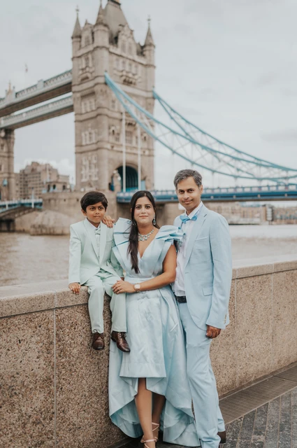London family photoshoot: a closer family portrait with Tower Bridge A closer family portrait beside the Thames with Tower Bridge rising behind the three of them during their London family photoshoot.