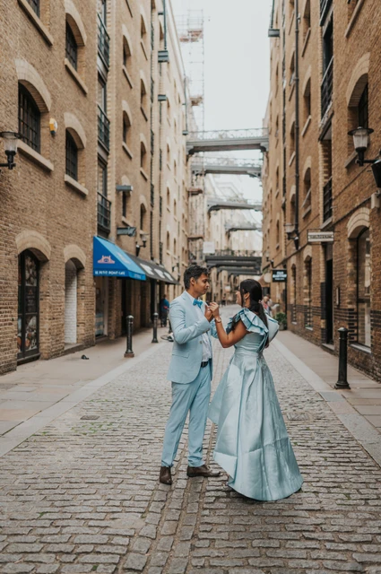 London family photoshoot: an embrace among the warehouse buildings A couple embracing in the middle of a cobbled lane between brick warehouse buildings during their London family photoshoot.