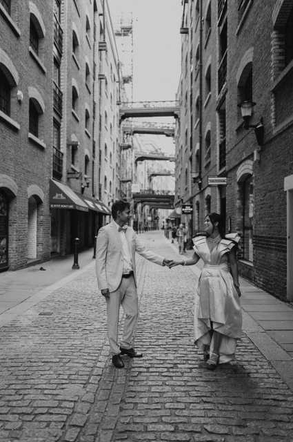 London family photoshoot: black-and-white movement along the lane Black-and-white photograph of a couple holding hands and moving through a cobbled lane during their London family photoshoot.