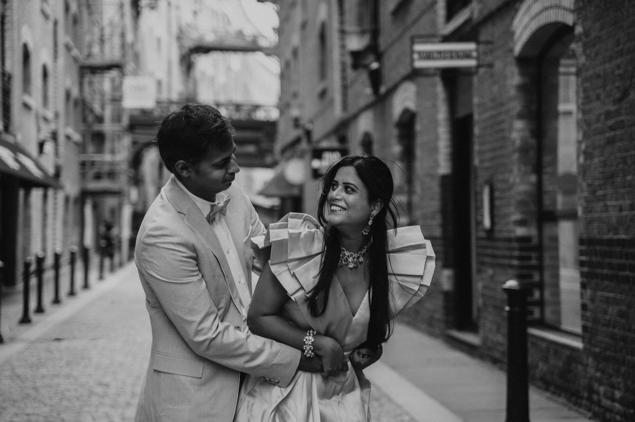 London family photoshoot: black-and-white smiles in the lane Black-and-white close portrait of a couple smiling together in a brick-lined lane during their London family photoshoot.