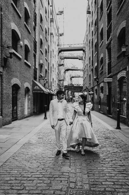London family photoshoot: black-and-white walk near Butler’s Wharf Black-and-white portrait of a couple walking together through a cobbled brick lane during their London family photoshoot.