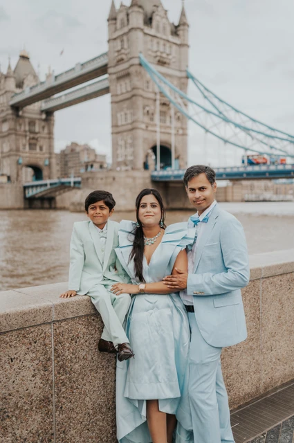 London family photoshoot: together in front of Tower Bridge A family of three facing the camera beside the Thames with Tower Bridge in the background during their London family photoshoot.