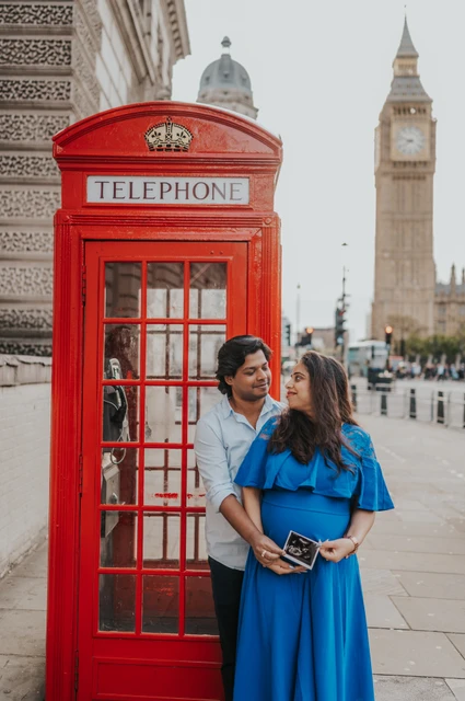 The couple hold an ultrasound scan beside a red telephone box with Big Ben behind them during a London maternity photoshoot.