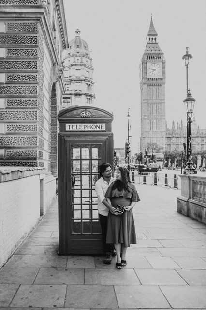 London maternity photoshoot beside a telephone box in black and white Black-and-white portrait of the couple beside a telephone box with Big Ben behind them during a London maternity photoshoot.