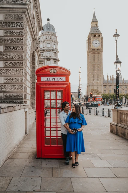 London maternity photoshoot with a red telephone box and Big Ben Wide portrait of the couple beside a red telephone box with Big Ben behind them during a London maternity photoshoot.