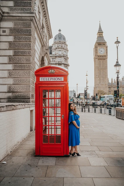 London maternity photoshoot with a wide Westminster street view The expectant mother stands beside a red telephone box below the view of Big Ben during a London maternity photoshoot.