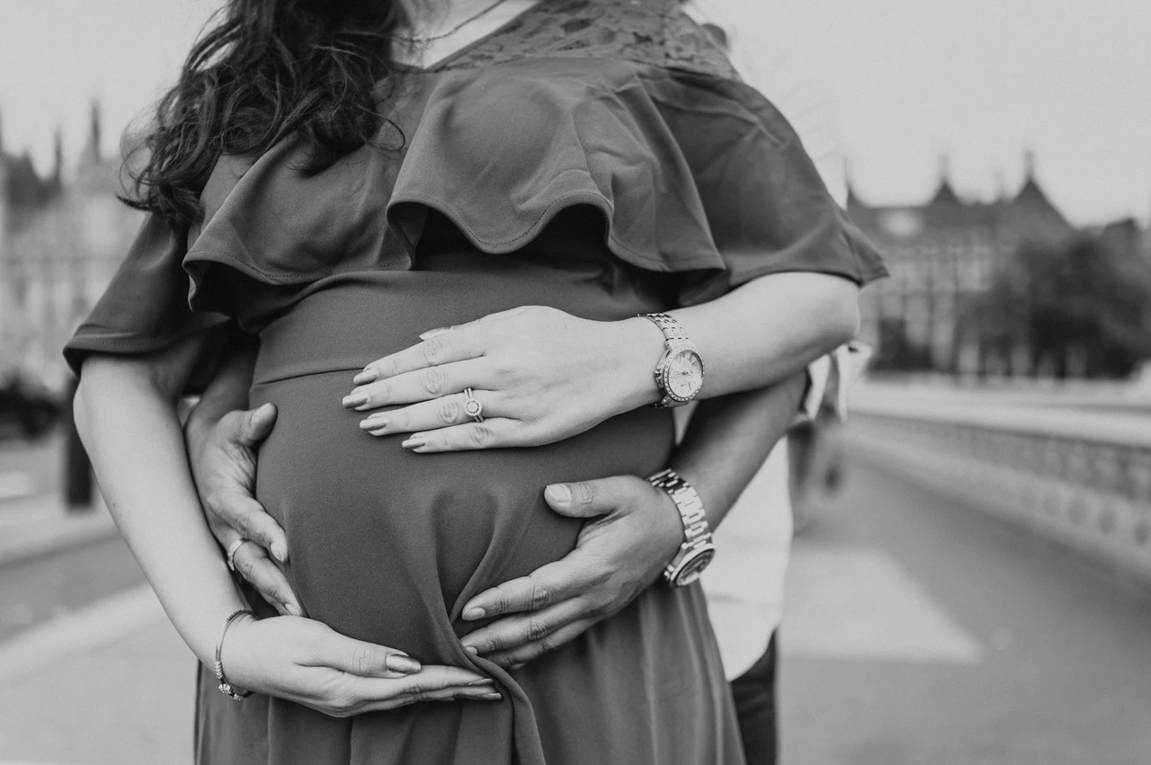 London maternity photoshoot with hands around the bump in black and white Black-and-white close-up of the couple's hands around the baby bump during a London maternity photoshoot on Westminster Bridge.