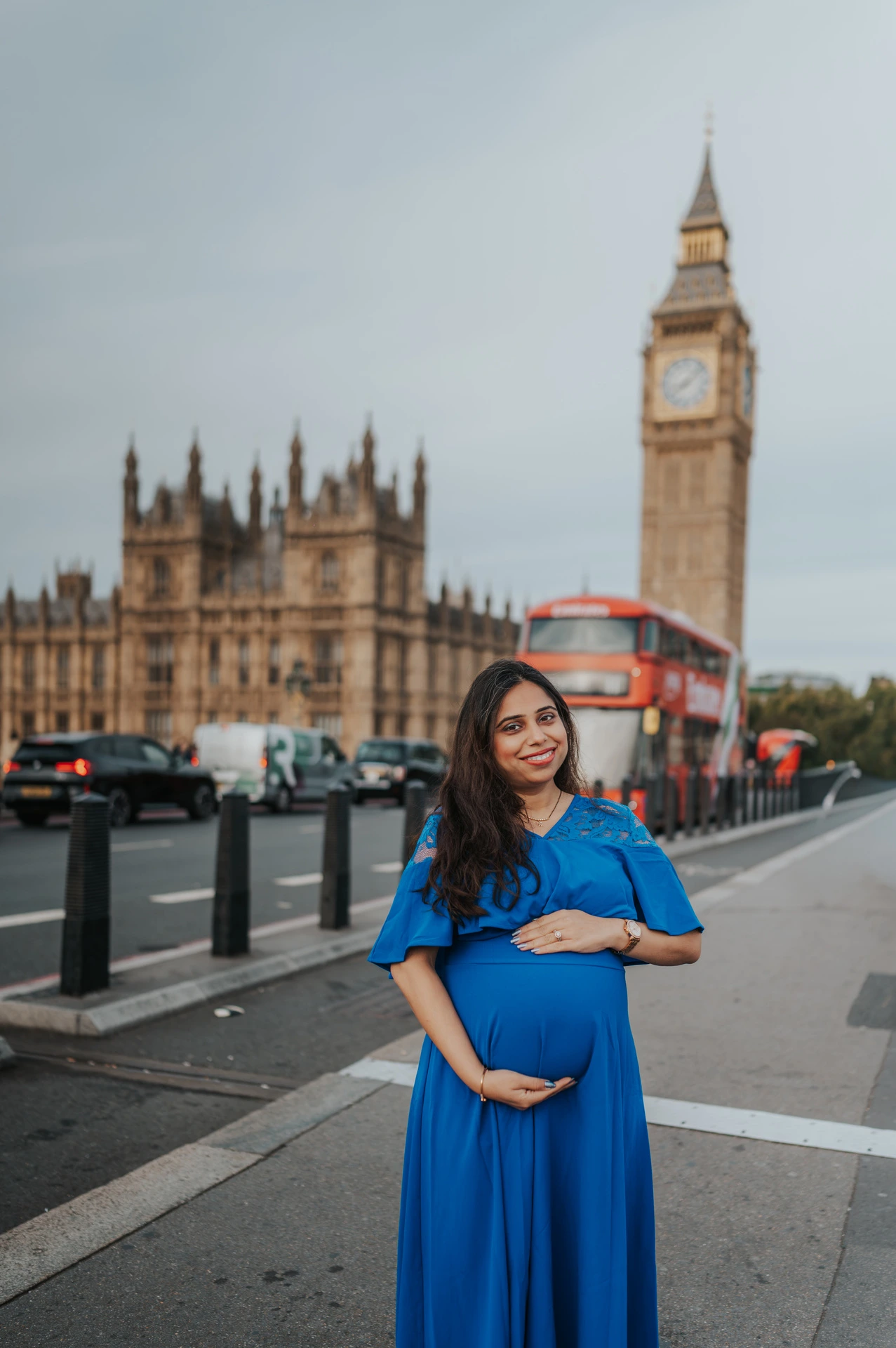 The expectant mother rests her hands above and below her bump with Big Ben and a red bus behind her during a London maternity photoshoot.