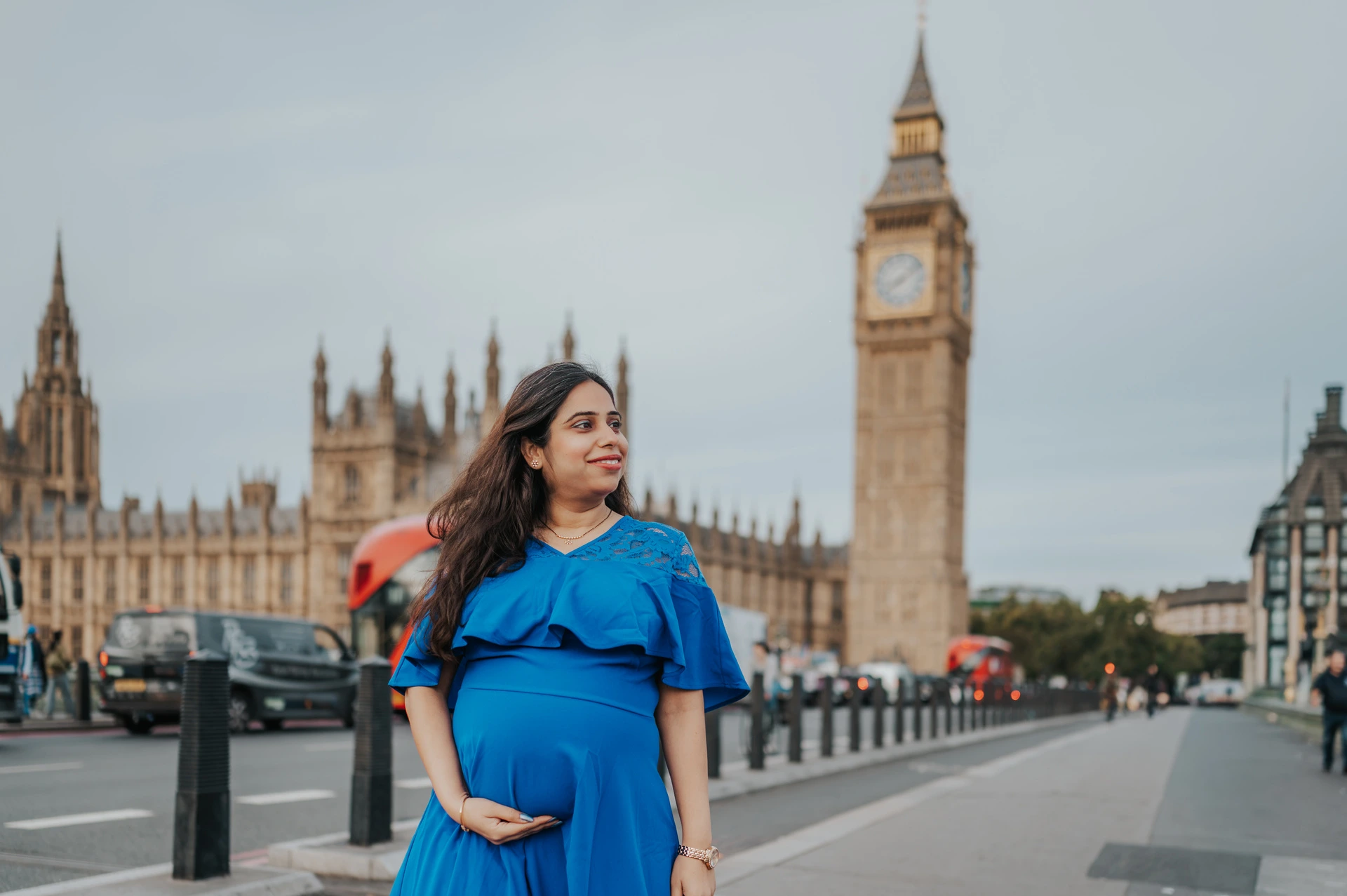 London maternity photoshoot in a blue dress with a wide Big Ben view Landscape portrait of the expectant mother in a blue dress with Big Ben and the Houses of Parliament during a London maternity photoshoot.