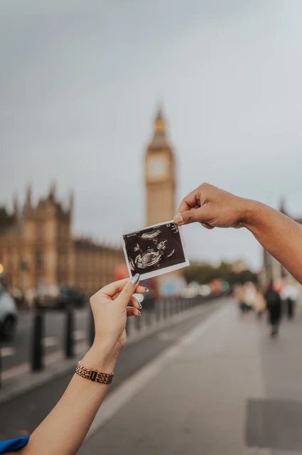 London maternity photoshoot with an ultrasound scan in front of Big Ben Hands hold an ultrasound scan in front of a softly blurred Big Ben during a London maternity photoshoot.