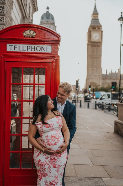 A close couple portrait by Big Ben at a London maternity photoshoot Close portrait of the couple looking at each other beside a red telephone box, with Big Ben behind, during their London maternity photoshoot.