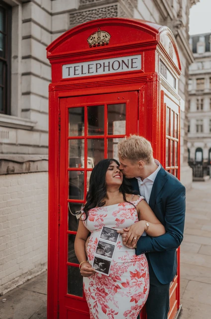 The ultrasound scan joins a London maternity photoshoot The couple sharing a close moment beside a red telephone box while she holds their ultrasound scan during a London maternity photoshoot.