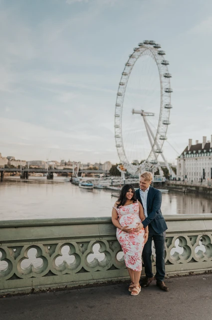 London maternity photoshoot beneath the London Eye skyline The couple together at Westminster Bridge with the London Eye rising above them during their London maternity photoshoot.