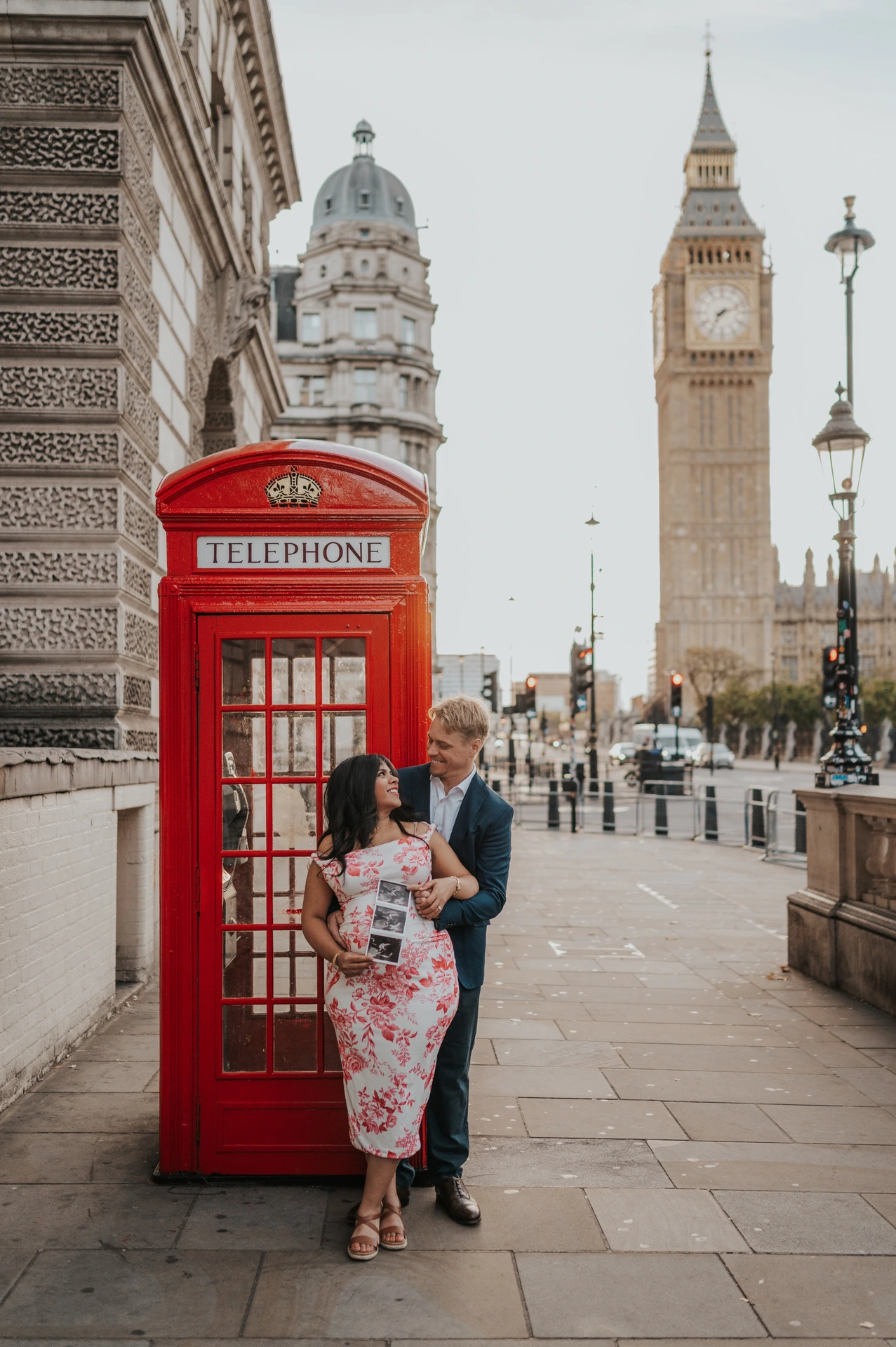 Full-length portrait of the couple together in front of a red telephone box and Big Ben during their London maternity photoshoot.
