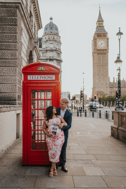 London maternity photoshoot with the Westminster telephone box Full-length portrait of the couple together in front of a red telephone box and Big Ben during their London maternity photoshoot.