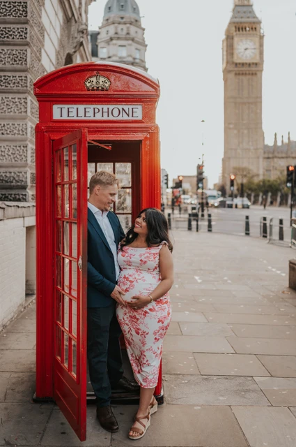 Big Ben beyond the doorway at a London maternity photoshoot The expectant couple standing in an open red telephone box doorway with Big Ben beyond during their London maternity photoshoot.
