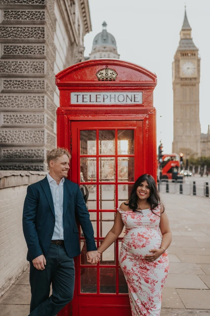 Smiles by Big Ben during a London maternity photoshoot Closer portrait of the couple smiling on either side of a red telephone box, with Big Ben in the background, during their London maternity photoshoot.