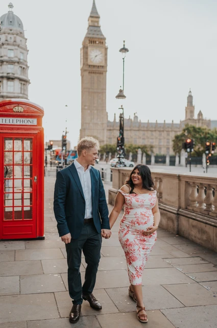 London maternity photoshoot along the Westminster balustrade Closer view of the couple walking beside the Westminster stone balustrade and a red telephone box during their London maternity photoshoot.