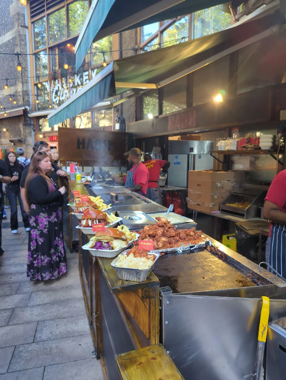 Hot food on a Borough Market counter with stallholders and visitors behind it