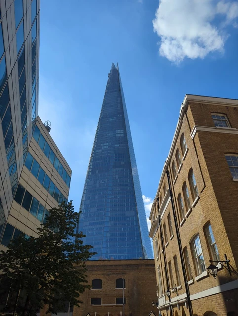 The glass Shard rising between lower brick and glass buildings near Borough Market