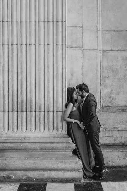 London proposal photoshoot: a column portrait in black and white Black-and-white photograph of the couple sharing a close moment beside one of the fluted stone columns at St Paul’s Cathedral during their London proposal photoshoot.
