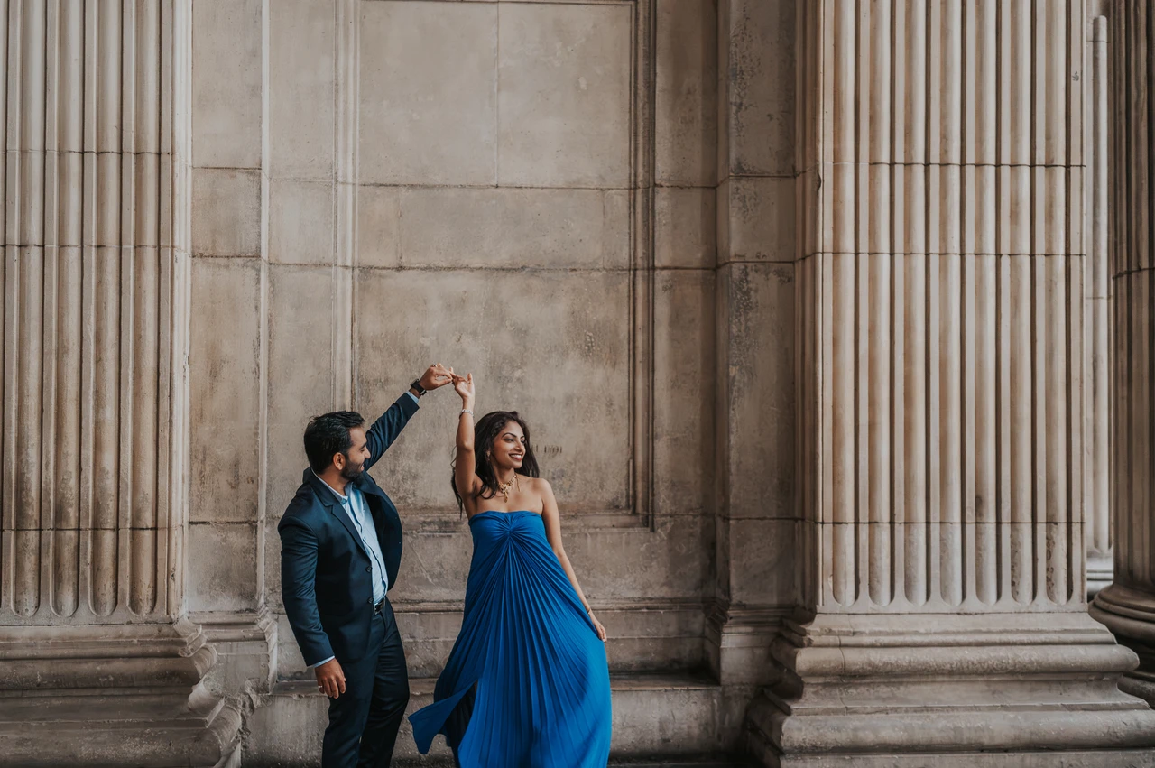 London proposal photoshoot: a wide portrait between the columns A wide view of the couple twirling between the fluted stone columns of St Paul’s Cathedral during their London proposal photoshoot.
