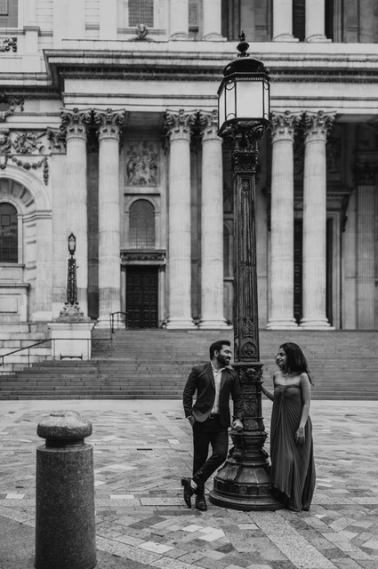 London proposal photoshoot: a cathedral lamp post in black and white Black-and-white photograph of the couple standing on either side of a traditional lamp post in front of St Paul’s Cathedral during their London proposal photoshoot.