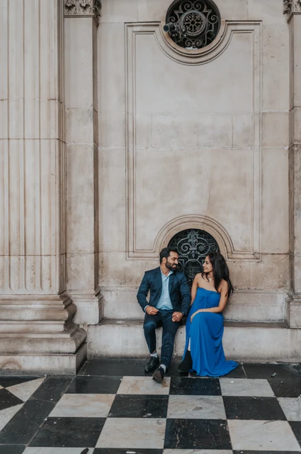 London proposal photoshoot: a portrait above checkerboard paving The couple sitting beside a decorative cathedral grille with the checkerboard floor below them at St Paul’s Cathedral during their London proposal photoshoot.