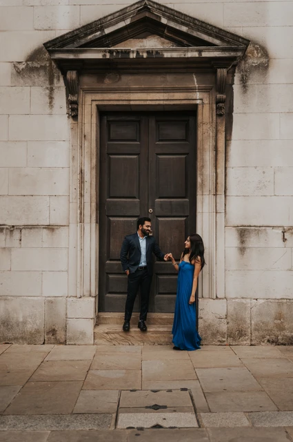 London proposal photoshoot: a stone doorway at St Paul’s Cathedral The couple beside a tall dark door set in the pale stone wall of St Paul’s Cathedral during their London proposal photoshoot.