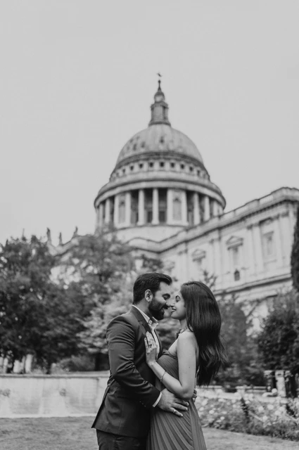 London proposal photoshoot: a garden kiss in black and white Black-and-white photograph of the couple sharing a kiss beneath the dome of St Paul’s Cathedral in Festival Gardens during their London proposal photoshoot.