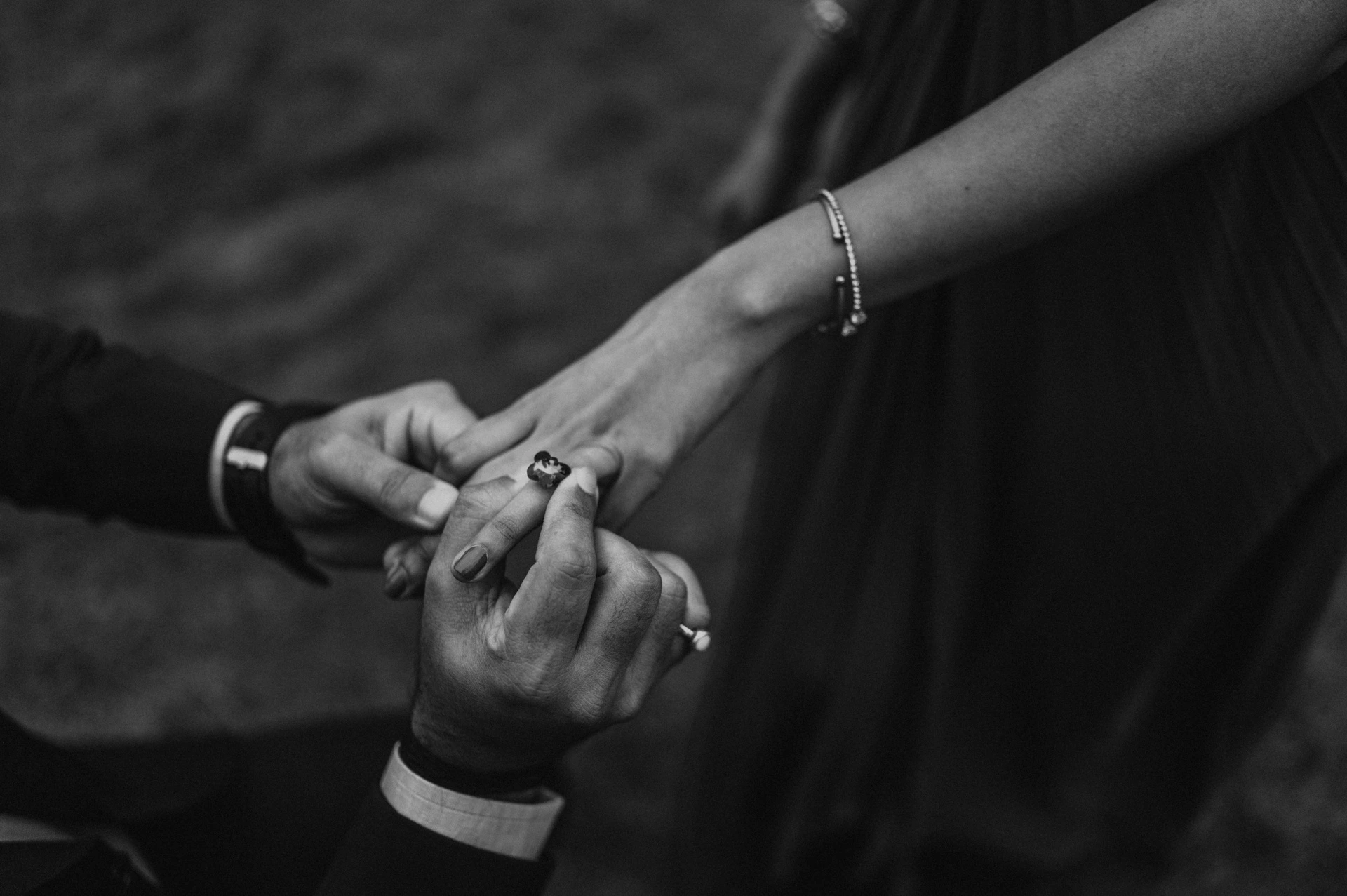 Black-and-white photograph of a close view of the engagement ring and the couple’s hands in Festival Gardens during their London proposal photoshoot.