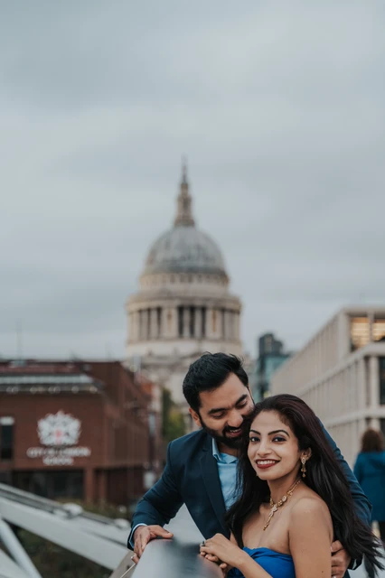 London proposal photoshoot: a close portrait on Millennium Bridge The couple close together on Millennium Bridge with the dome of St Paul’s Cathedral behind them during their London proposal photoshoot.
