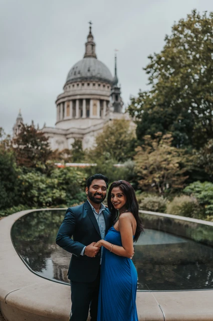 London proposal photoshoot: smiles at the Reflection Garden The couple smiling together by the Reflection Garden pool with St Paul’s Cathedral behind them during their London proposal photoshoot.