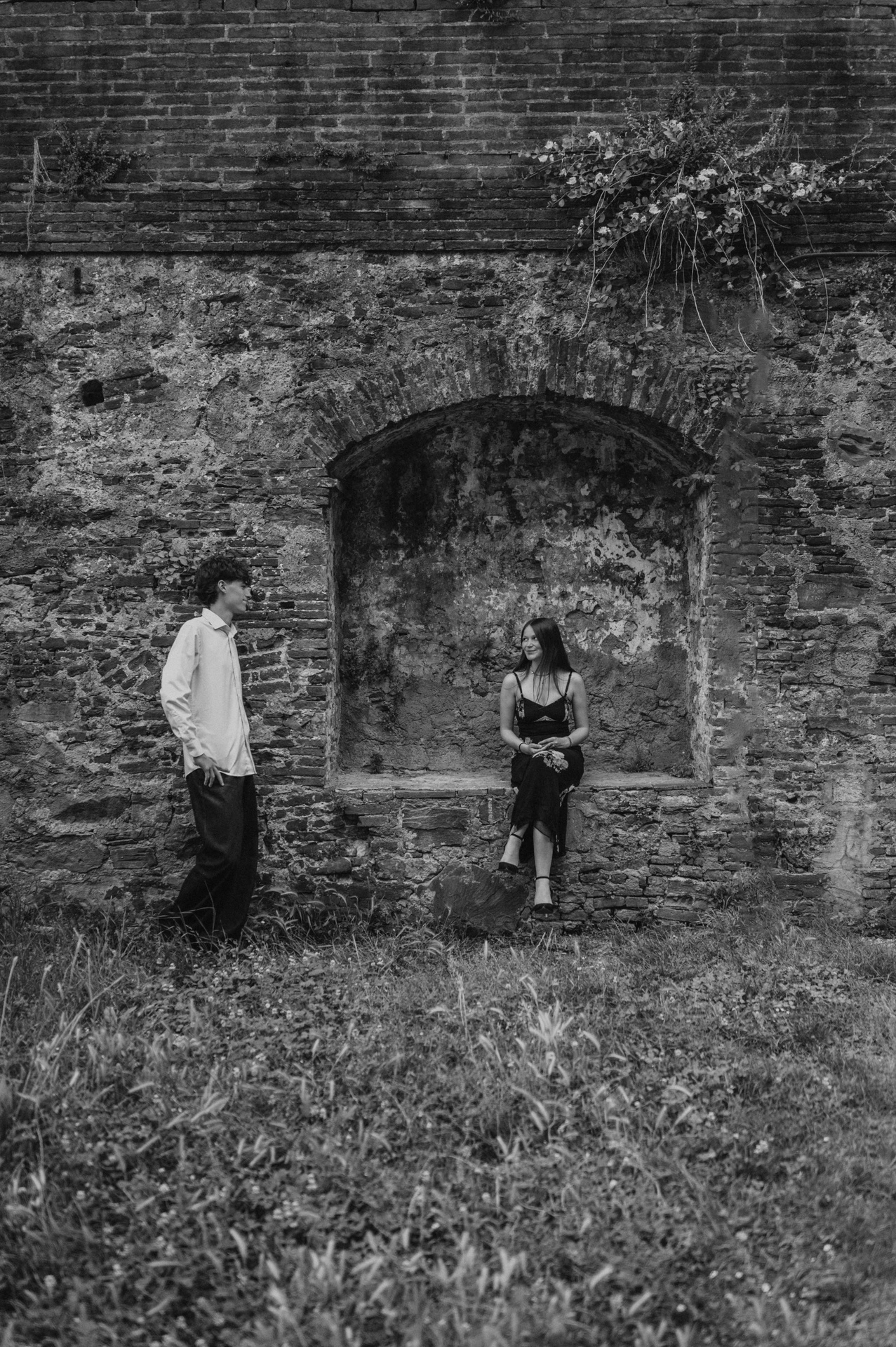Black-and-white portrait of Alice and Pablo beside an arched recess in the old city walls. From Alice and Pablo’s Lucca anniversary photoshoot.
