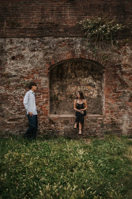 Lucca couple photoshoot beside a brick arch Alice and Pablo stand on either side of a small brick arch in the city walls. From Alice and Pablo’s Lucca anniversary photoshoot.