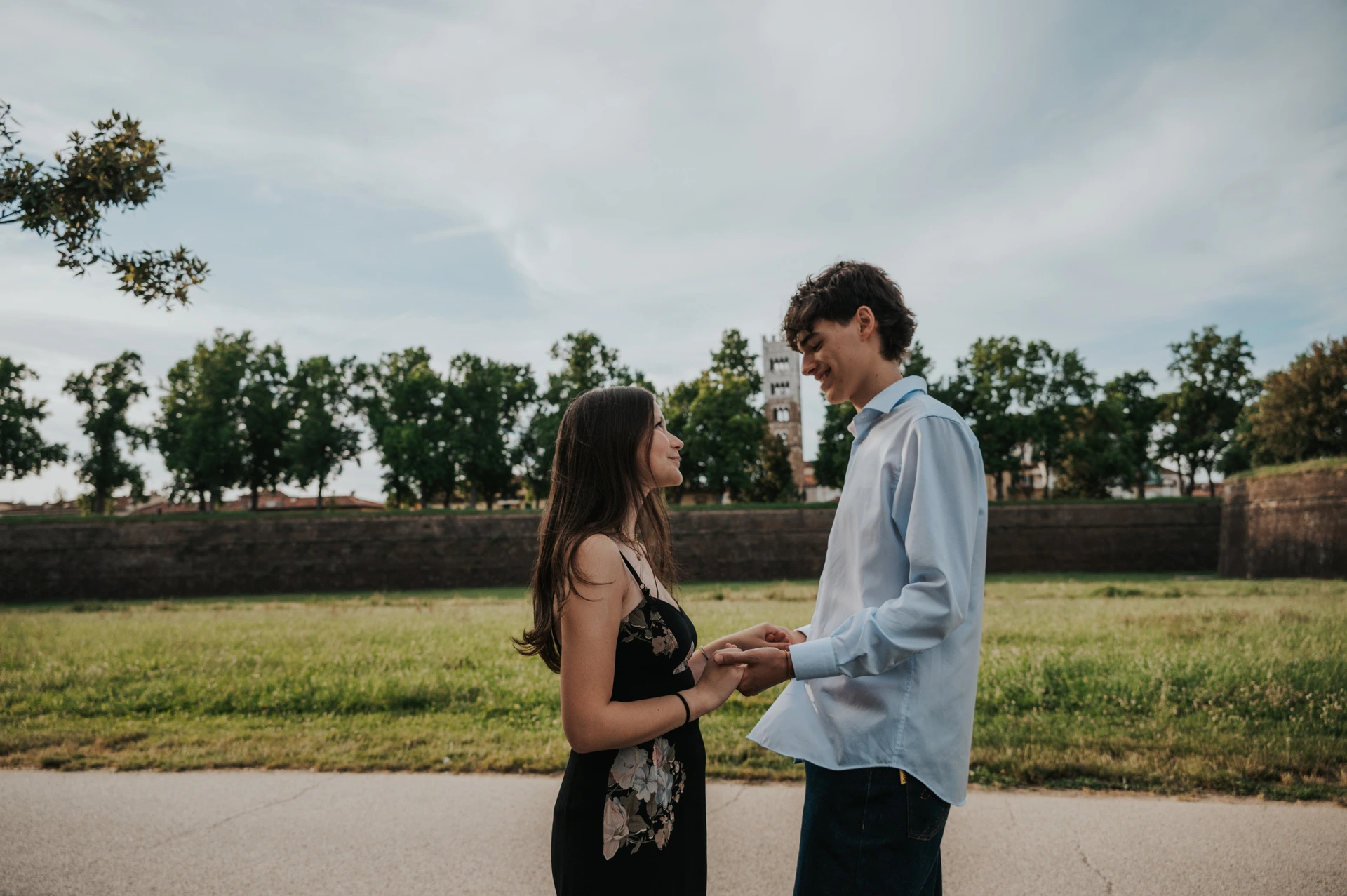 Alice and Pablo face one another on the city walls with the tower of San Martino beyond the trees. From Alice and Pablo’s Lucca anniversary photoshoot.