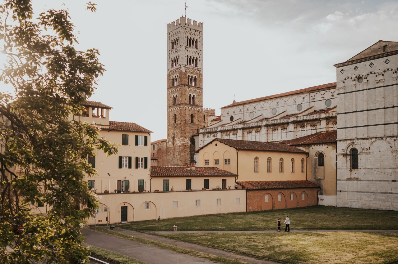 Duomo di San Martino setting for a Lucca photoshoot Wide view of the Duomo di San Martino and its bell tower beyond the grass and warm-toned buildings. From Alice and Pablo’s Lucca anniversary photoshoot.