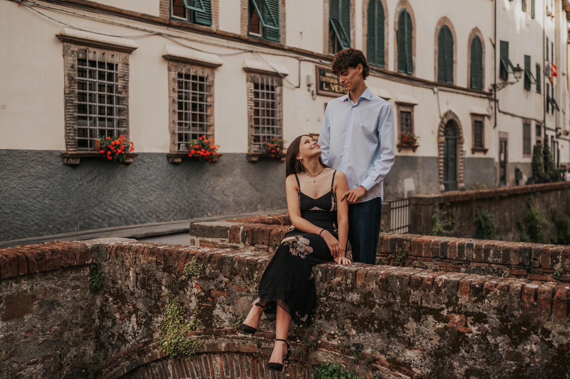 Alice and Pablo share a portrait on the small brick bridge beside Via del Fosso’s shuttered buildings. From Alice and Pablo’s Lucca anniversary photoshoot.