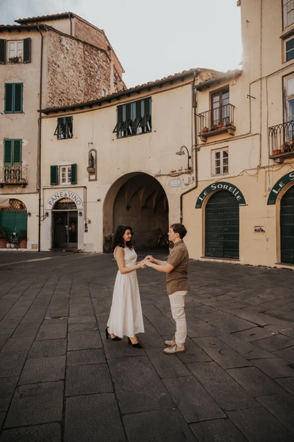 Lucca couple photoshoot: a moment together in Piazza dell’Anfiteatro The couple facing each other and holding hands in the open space of Piazza dell’Anfiteatro during a couple photoshoot in Lucca.