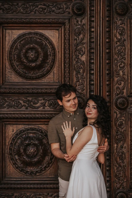 Lucca couple photoshoot: a close portrait beside San Martino’s carved doors The couple embracing in front of the Duomo di San Martino’s richly carved wooden doors during a couple photoshoot in Lucca.
