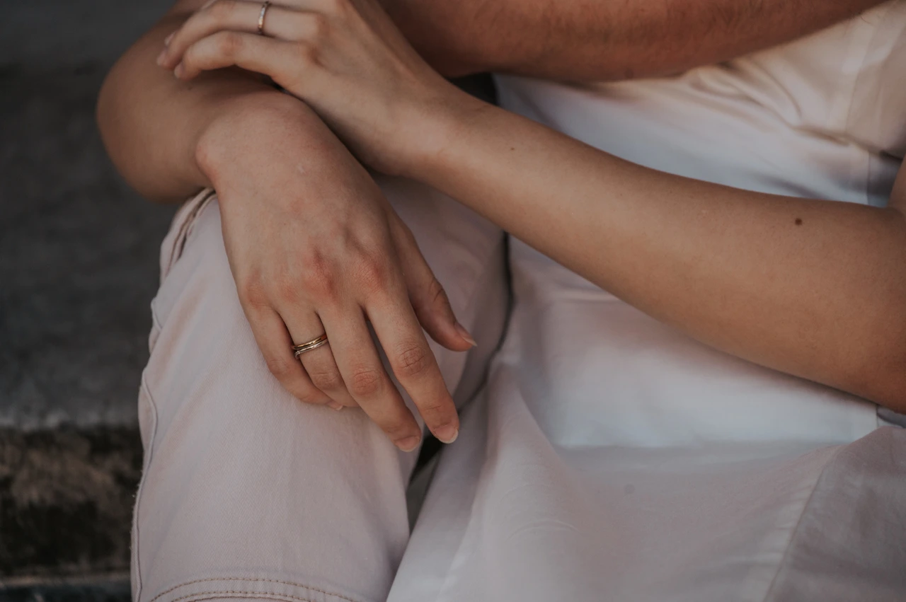 Lucca couple photoshoot: hands resting together on a white dress A close detail of the couple’s hands resting together on the woman’s white dress beside the Duomo di San Martino during a couple photoshoot in Lucca.