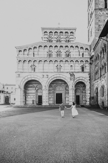 Lucca couple photoshoot: the open square outside San Martino in black and white Black-and-white photograph of the couple standing together in the open square in front of the Duomo di San Martino during a couple photoshoot in Lucca.
