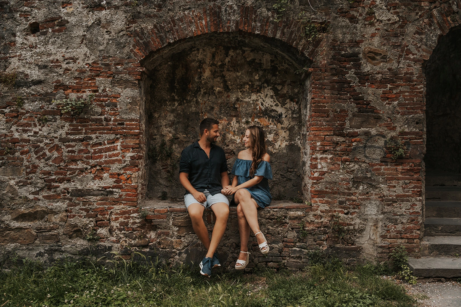 Couple seated in a brick wall niche in Lucca