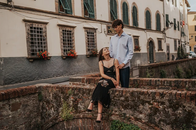 Woman seated beside her partner on a Via del Fosso bridge