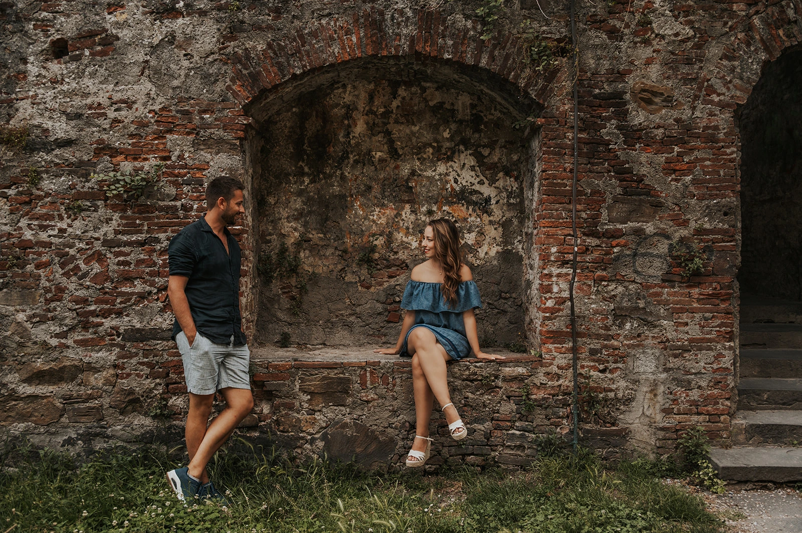 Couple chatting beside an old brick niche in Lucca