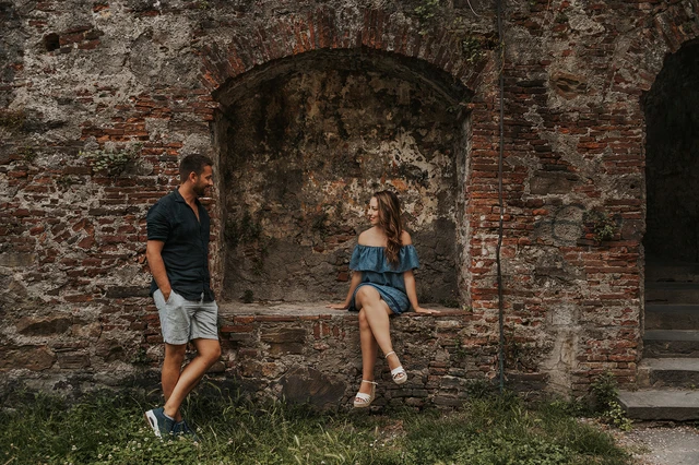Couple chatting beside an old brick niche in Lucca